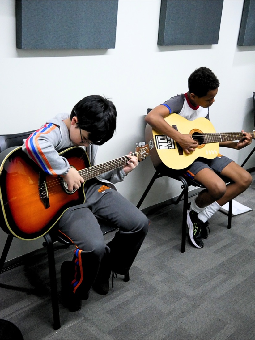 Alunos tocando violão na aula de música da MZ