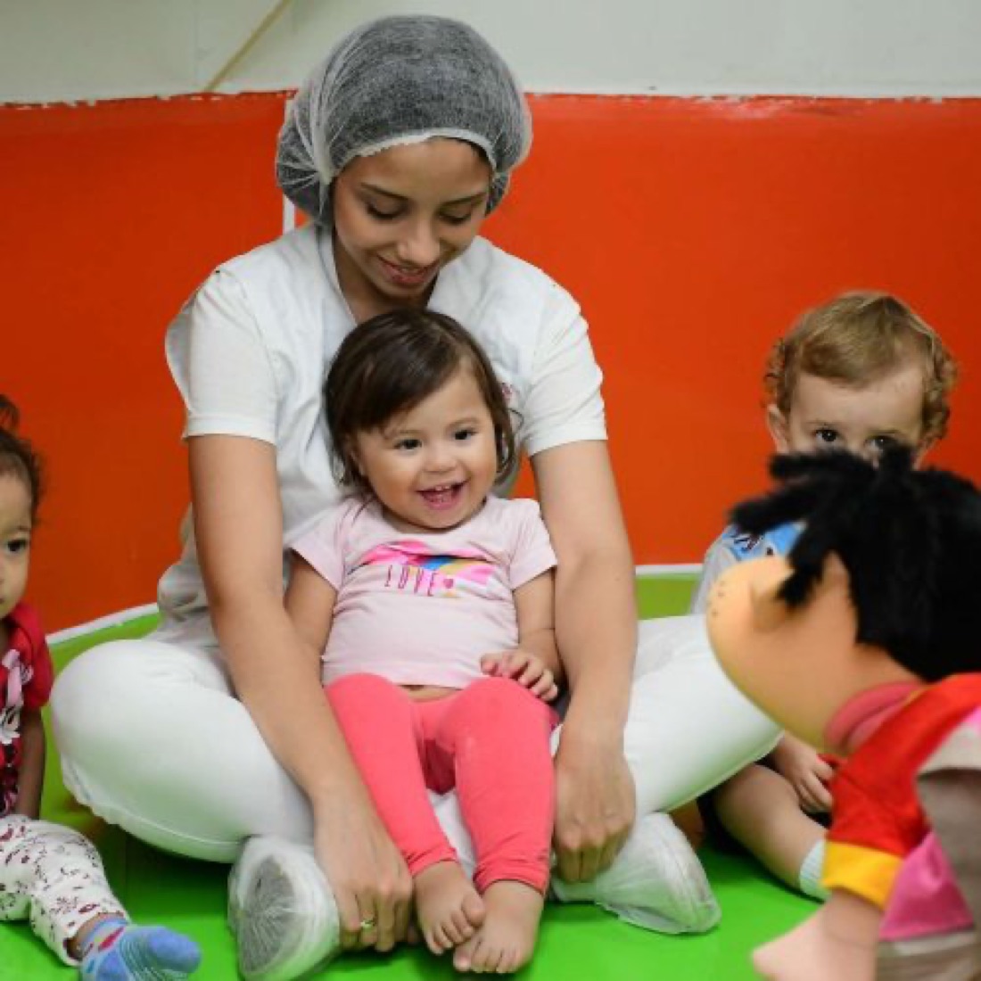 Berçarista da MZ School brincando com bebês em sala de estimulação