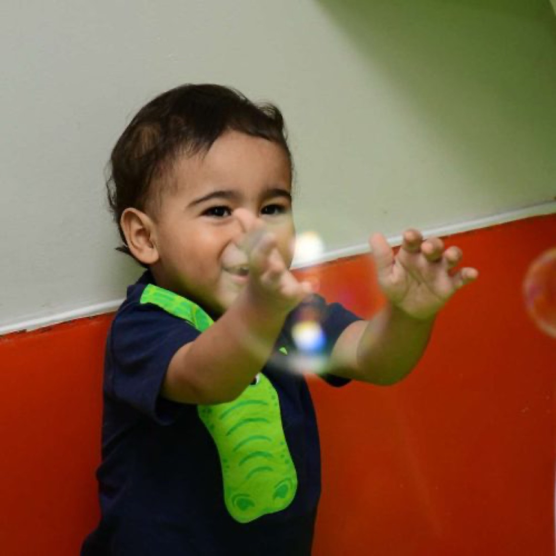 Bebê brincando com bolhas de sabão na área de estimulação
