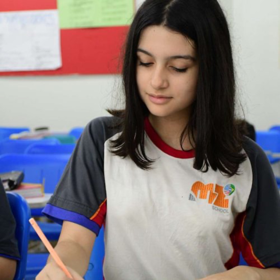 Aluna do Fundamental II escrevendo em sala de aula