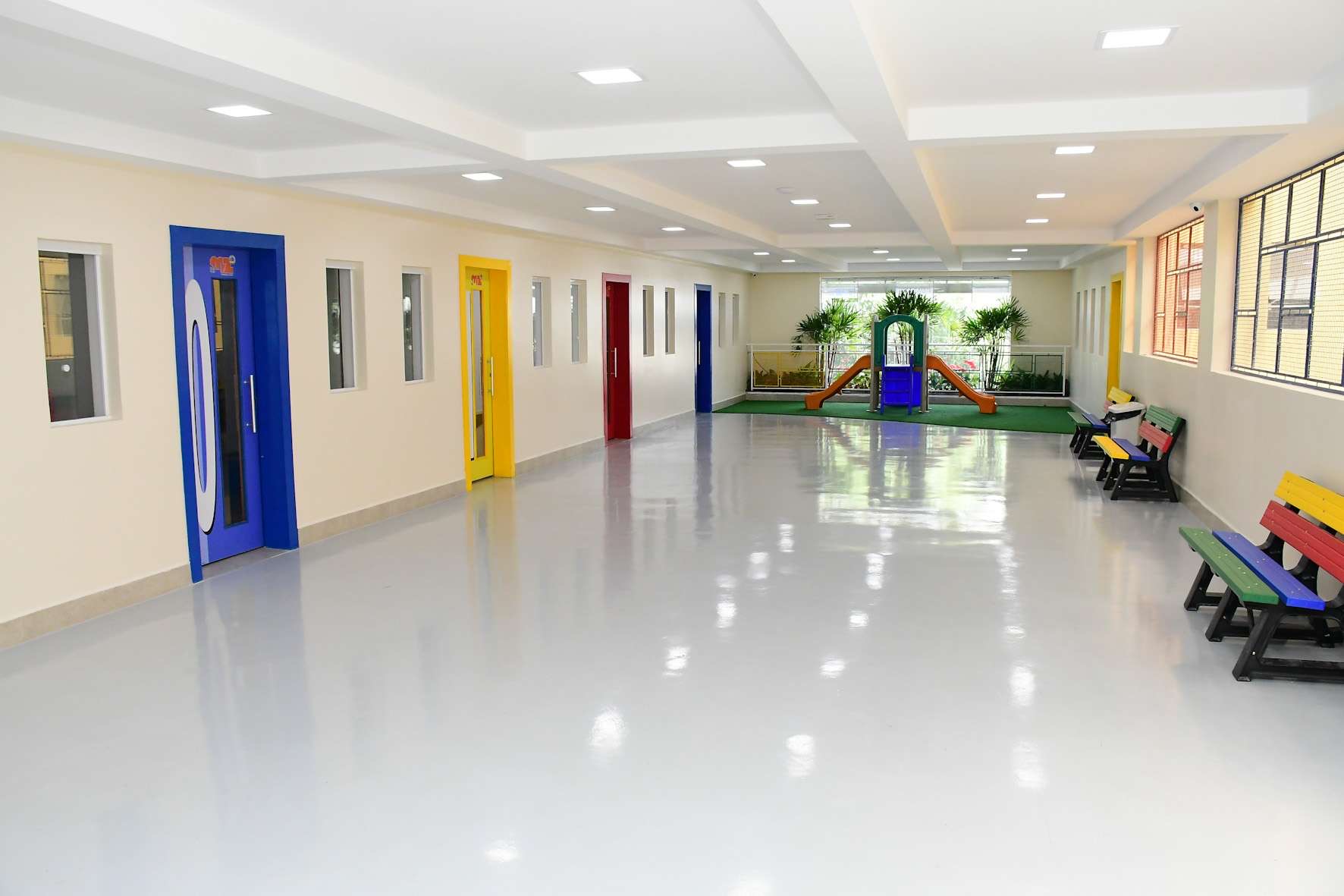 Corredor colorido da Educação Infantil da MZ School com playground ao fundo