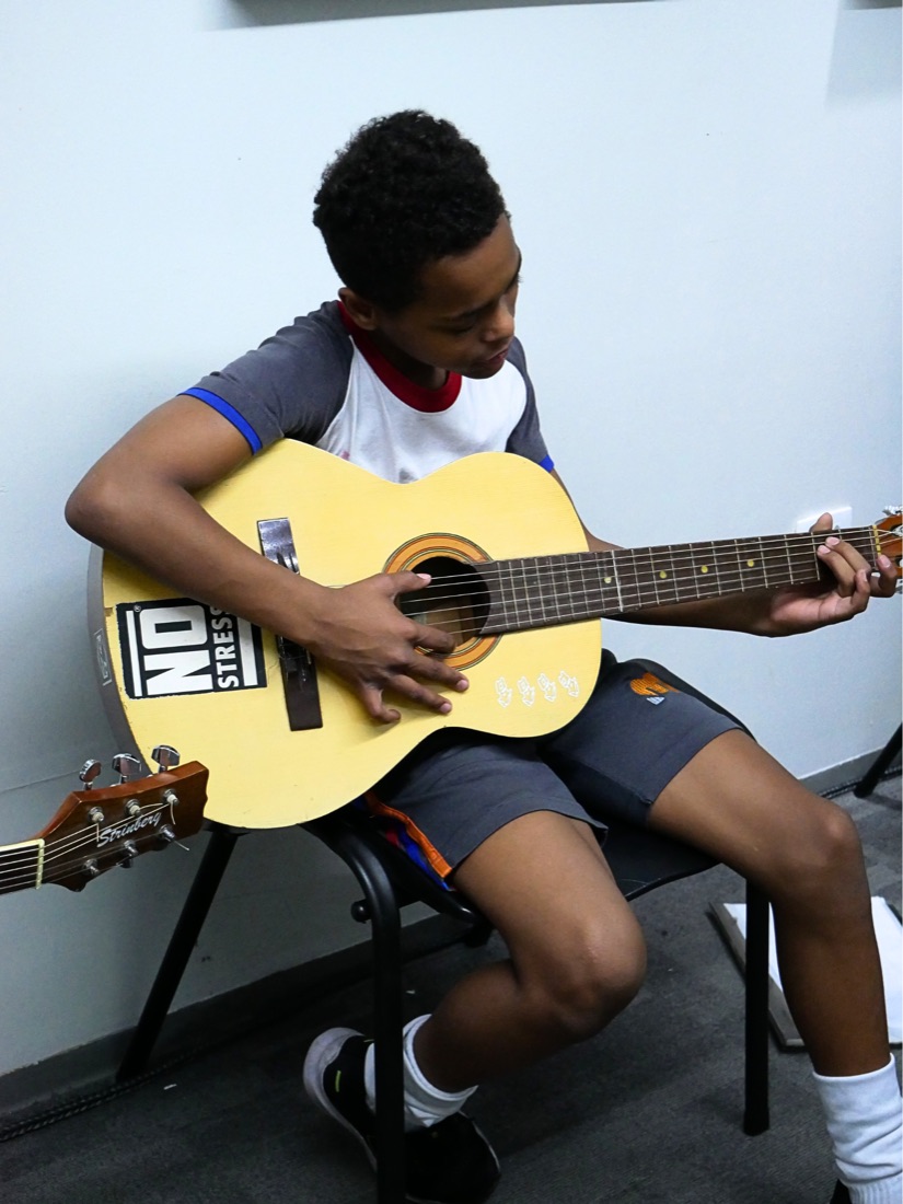 Aluno tocando violão na aula de música
